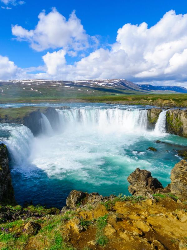 a waterfall is surrounded by rocks and mountains in the middle of a river .