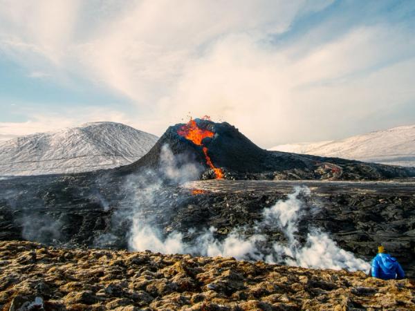 Fagradalsfjall Volcano erupting with a man watching from the distance