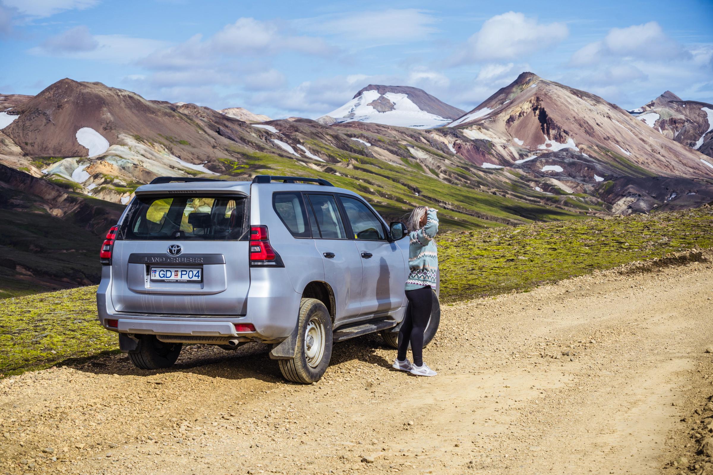 Land Cruiser – Heckansicht Toyota Land Cruiser in der Dreiviertelansicht von hinten auf einer Schotterstraße mit Bergen im Hintergrund