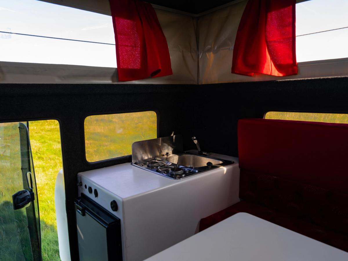 Kitchen Unit Side Angle Kitchen unit with stove, sink and fridge below, next to a red bench seat