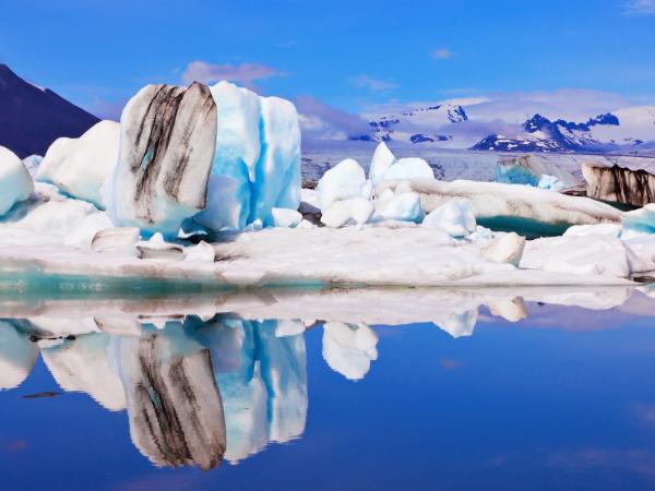 un iceberg se reflétant dans l'eau bleue par une journée claire