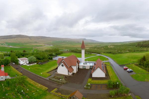 an aerial view of a church in the middle of a field with mountains in the background .