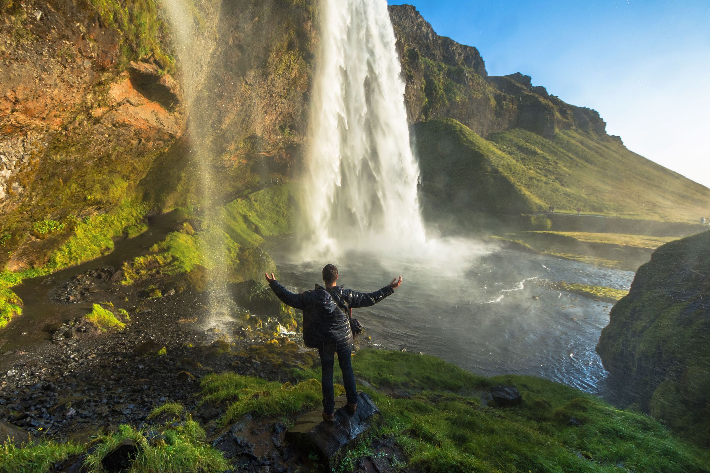 a man at the base of a waterfall