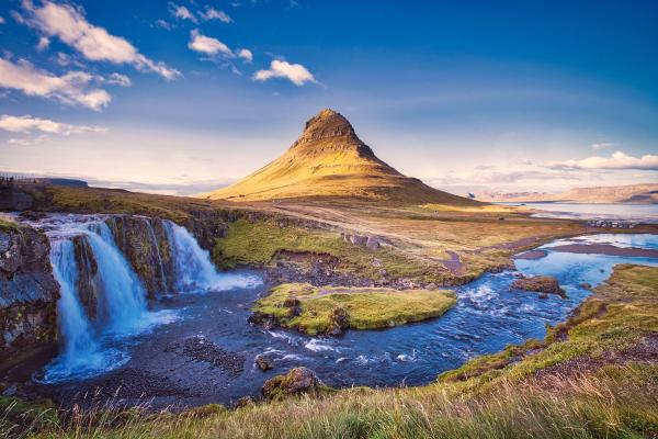 there is a waterfall in the foreground and a mountain in the background .