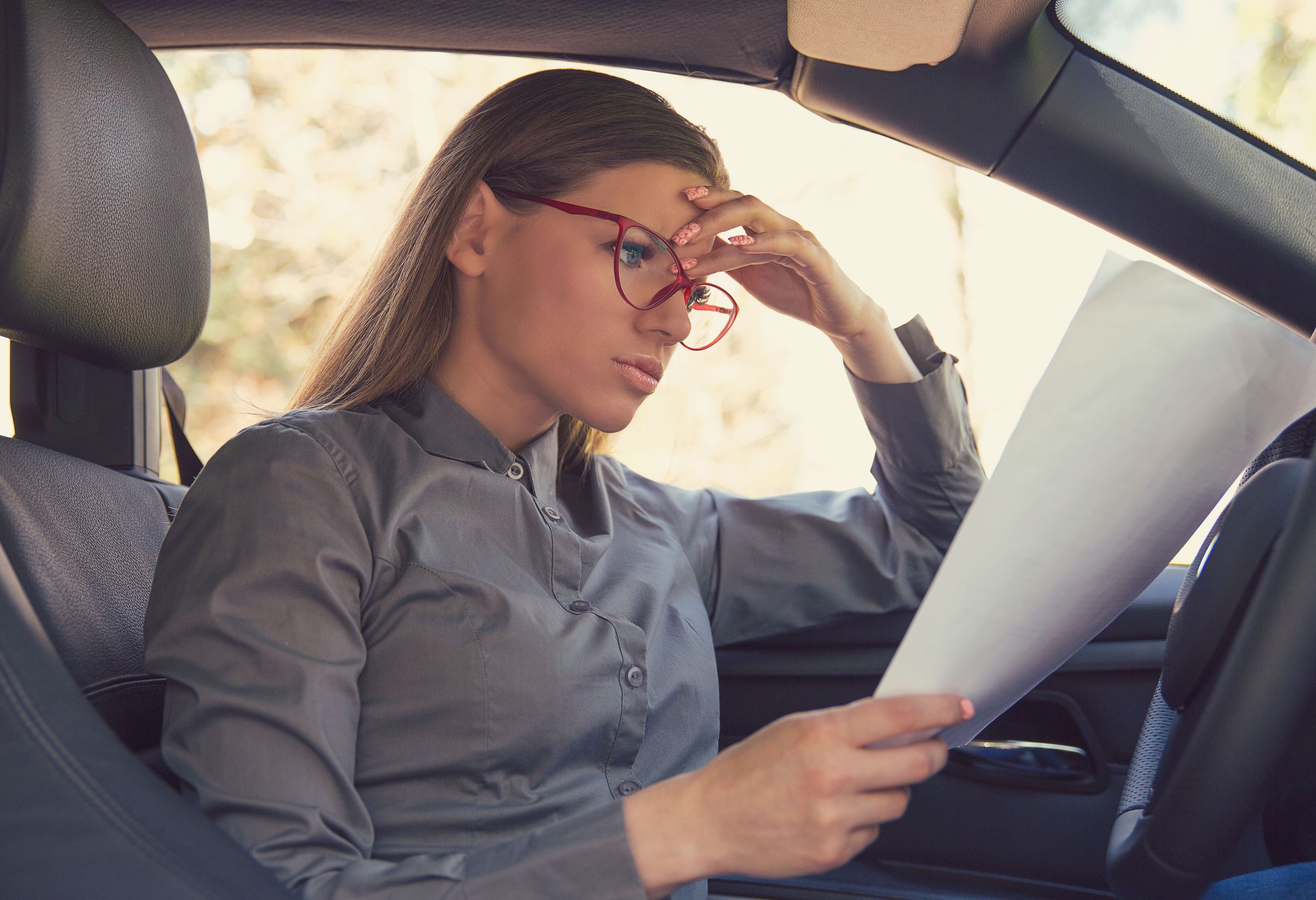 A woman reading a car rental agreement paper in a rental car in Iceland