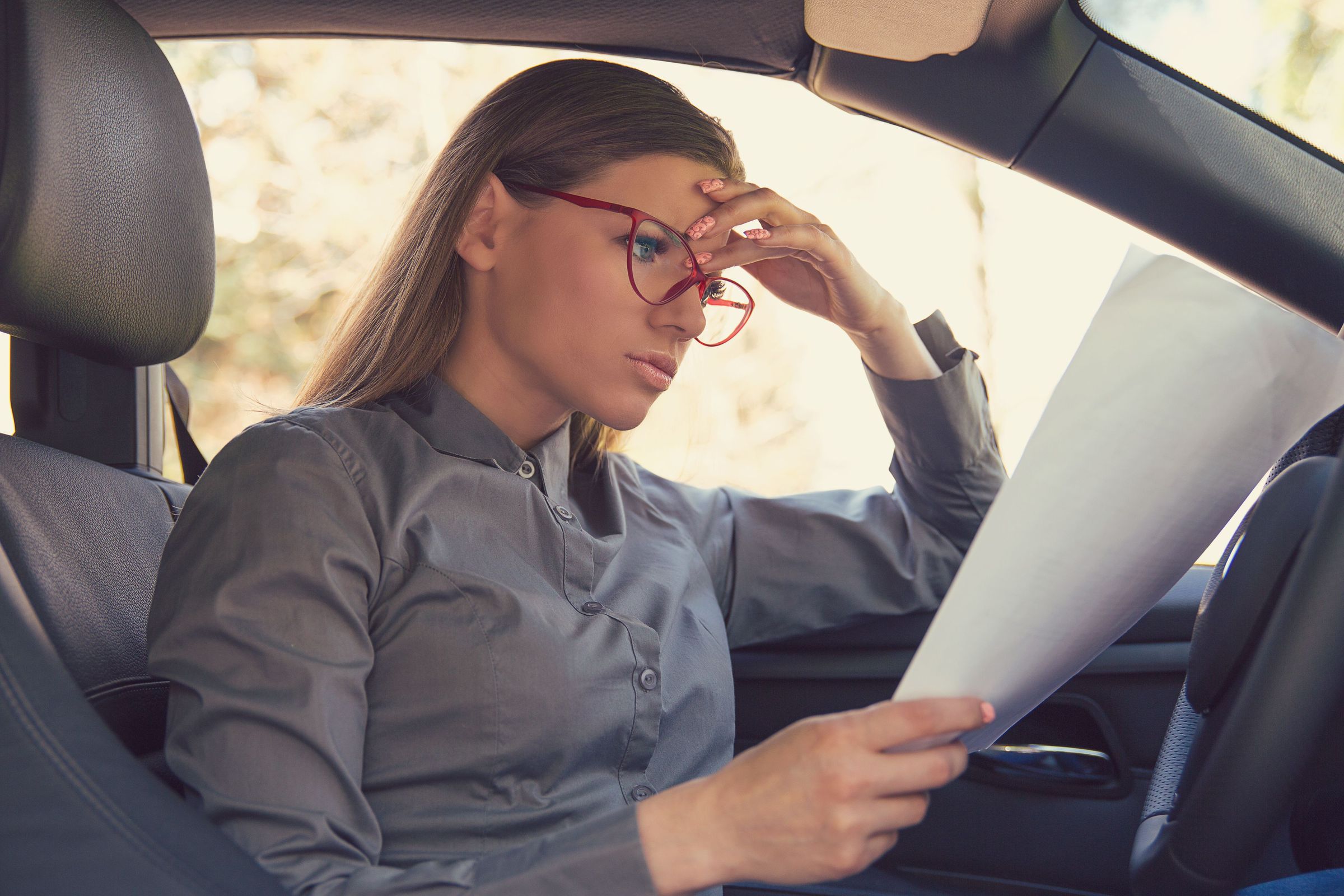 Woman reading car rental agreement paper in Iceland rental car A woman reading a car rental agreement paper in a rental car in Iceland