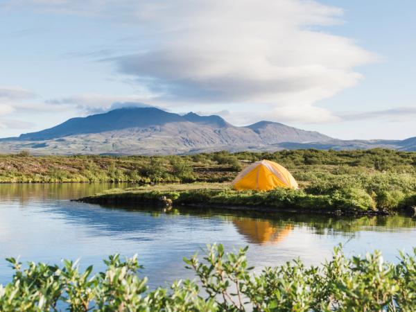una tienda de campaña amarilla junto a un lago