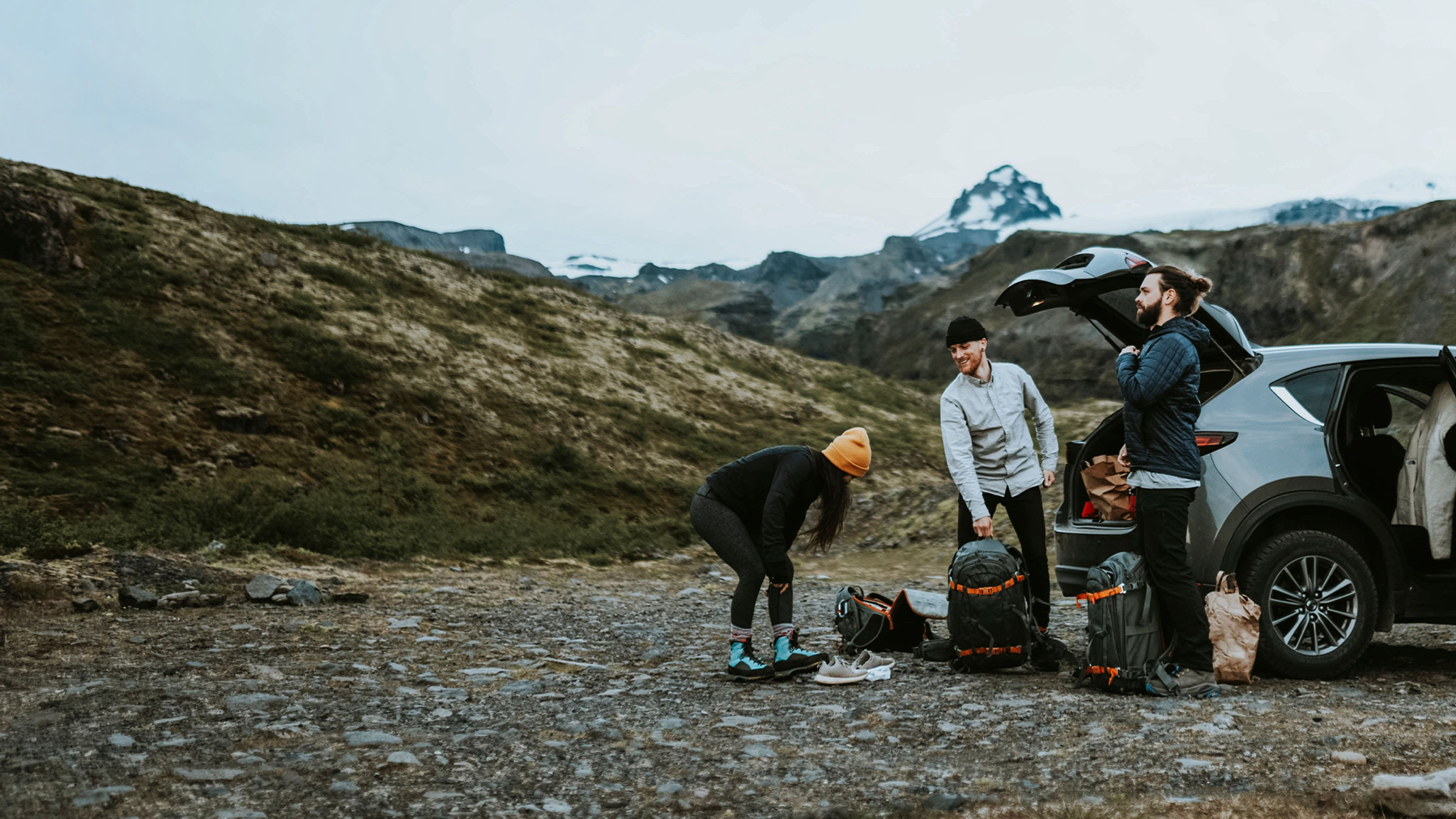 Three friends with their baggage outside their car rental in Iceland