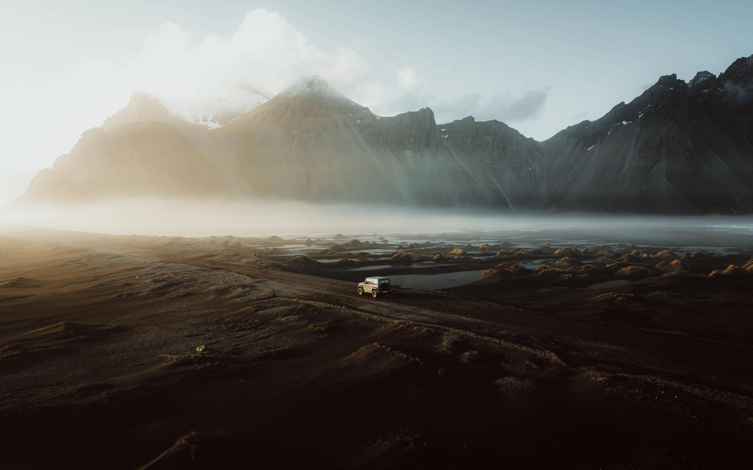 an aerial view of a car driving down a dirt road in the mountains .