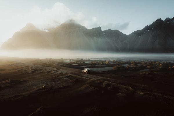 an aerial view of a car driving down a dirt road in the mountains .