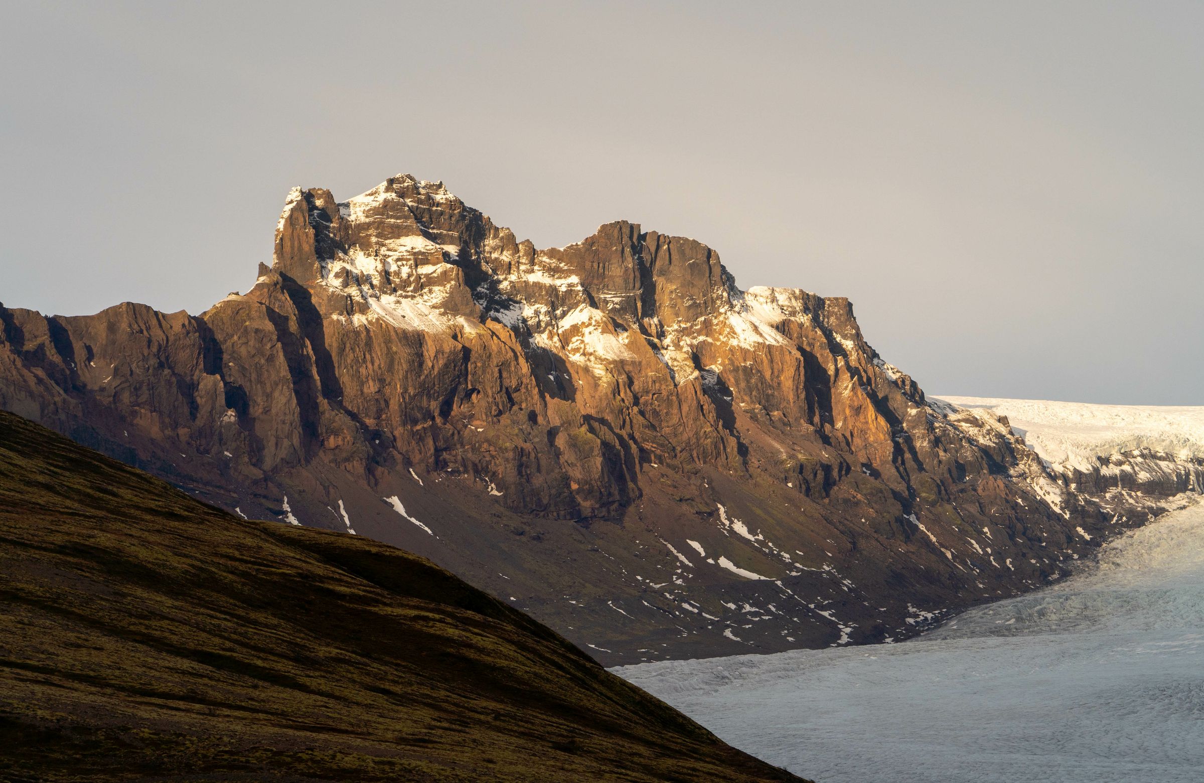 una montaña cubierta de nieve y hielo con un glaciar en primer plano.