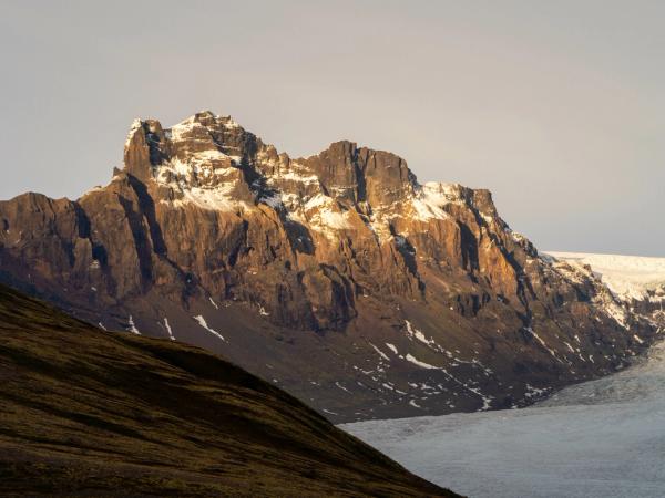 una montaña cubierta de nieve y hielo con un glaciar en primer plano.