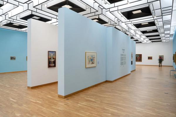 a museum with a lot of paintings on the walls and a wooden floor .