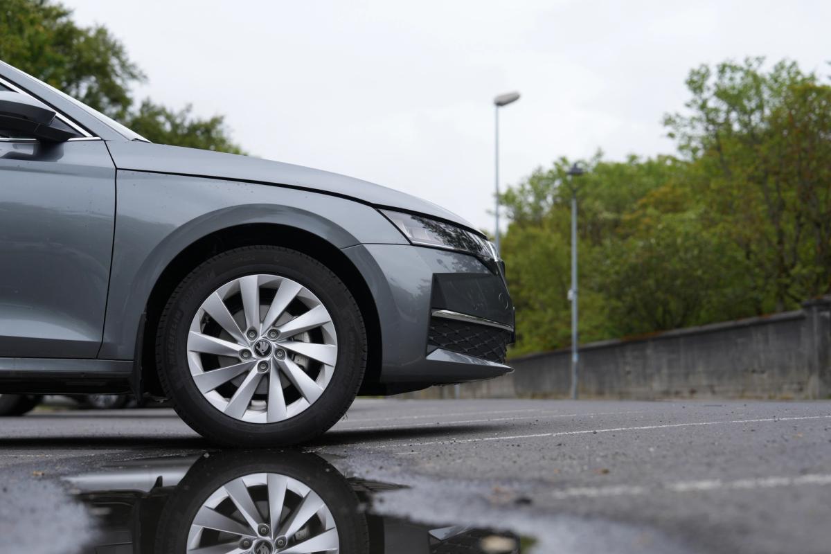 Nærmynd af framhjóli á Skoda Octavia-stationbíl með speglun í blautu malbikinu