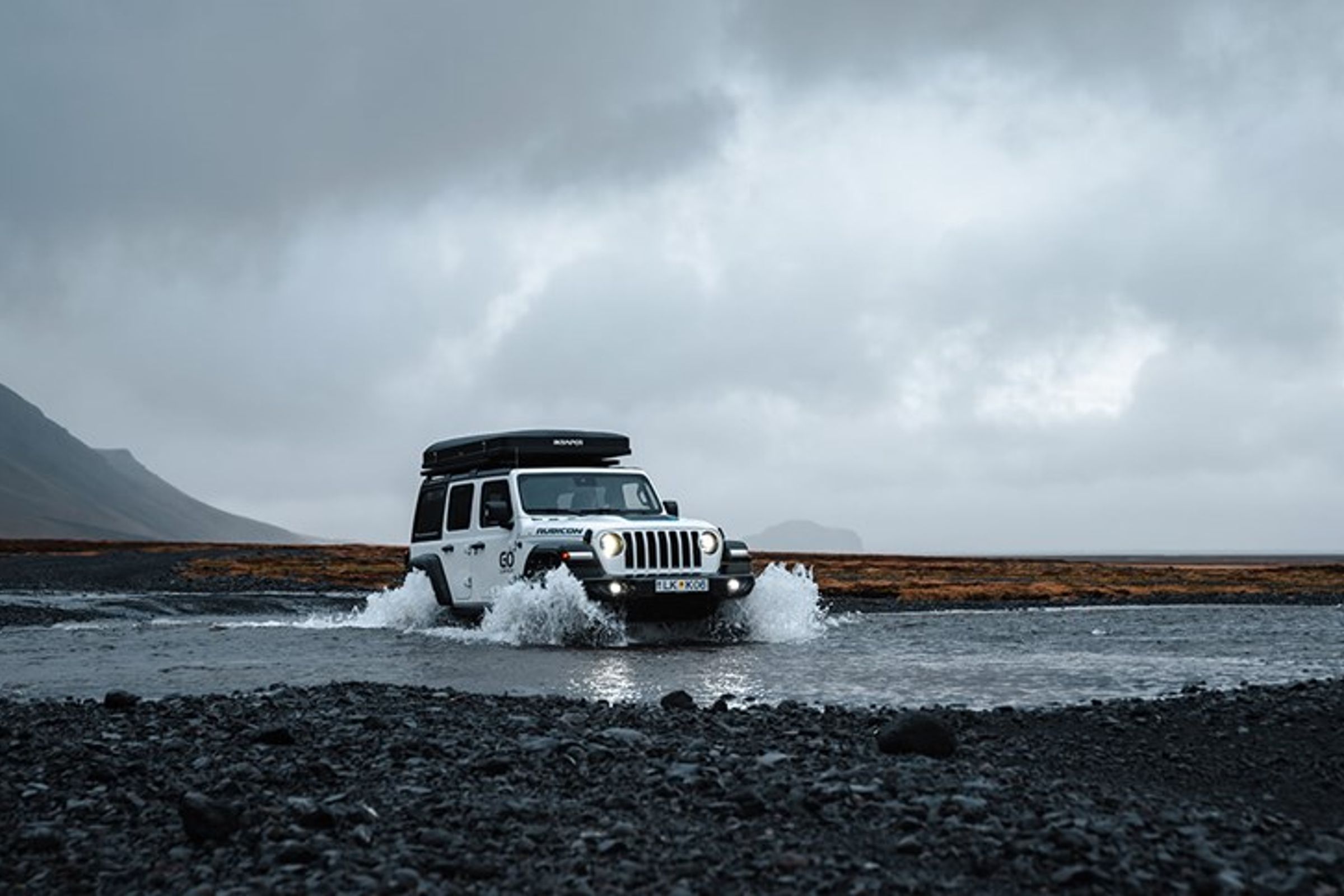 un jeep blanco está cruzando un río por un camino rocoso.