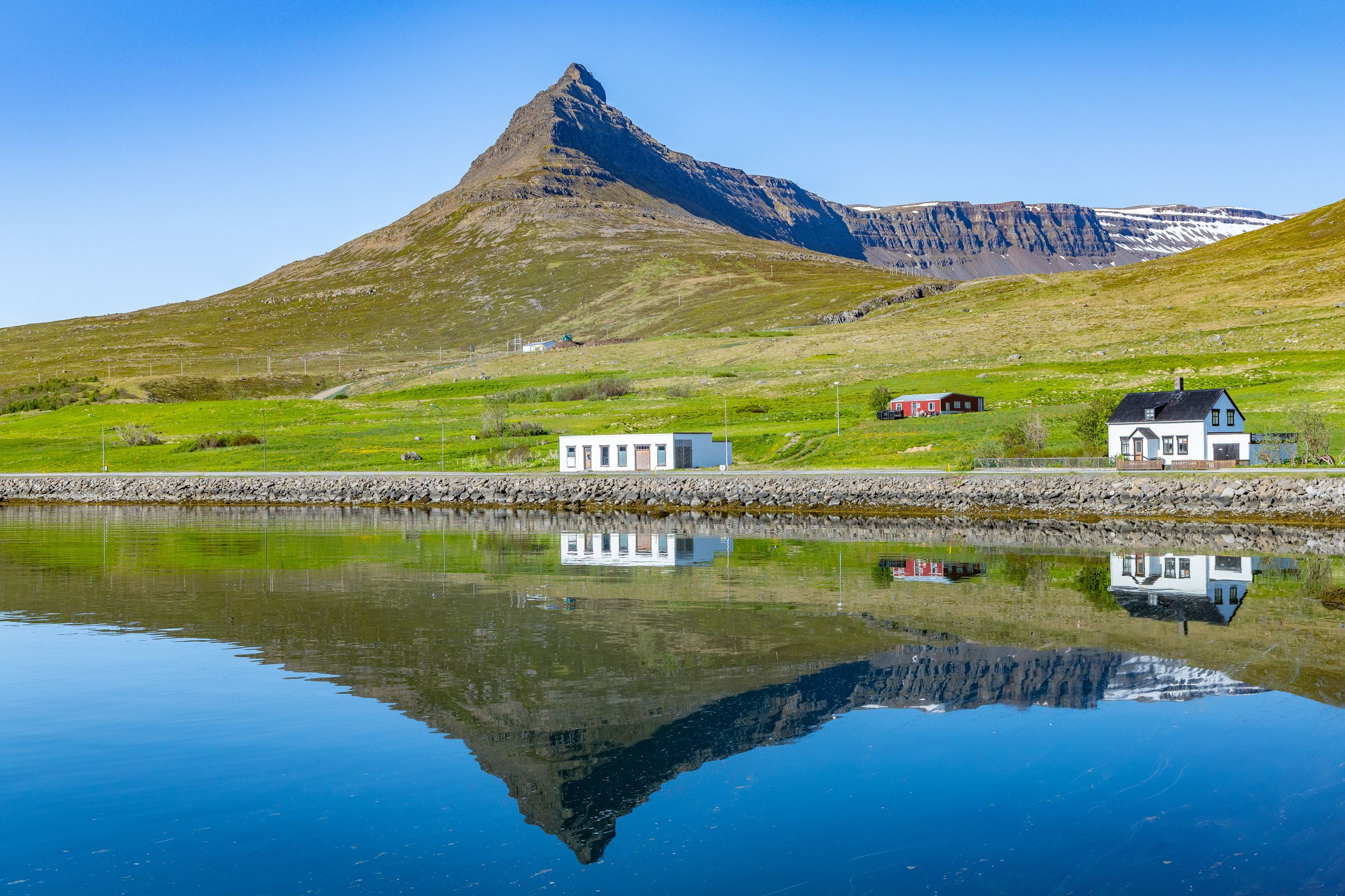 une maison se reflète dans un lac avec une montagne en arrière-plan, Súðavík