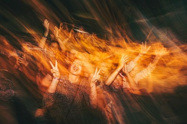 a group of people are dancing at a concert and making peace signs .