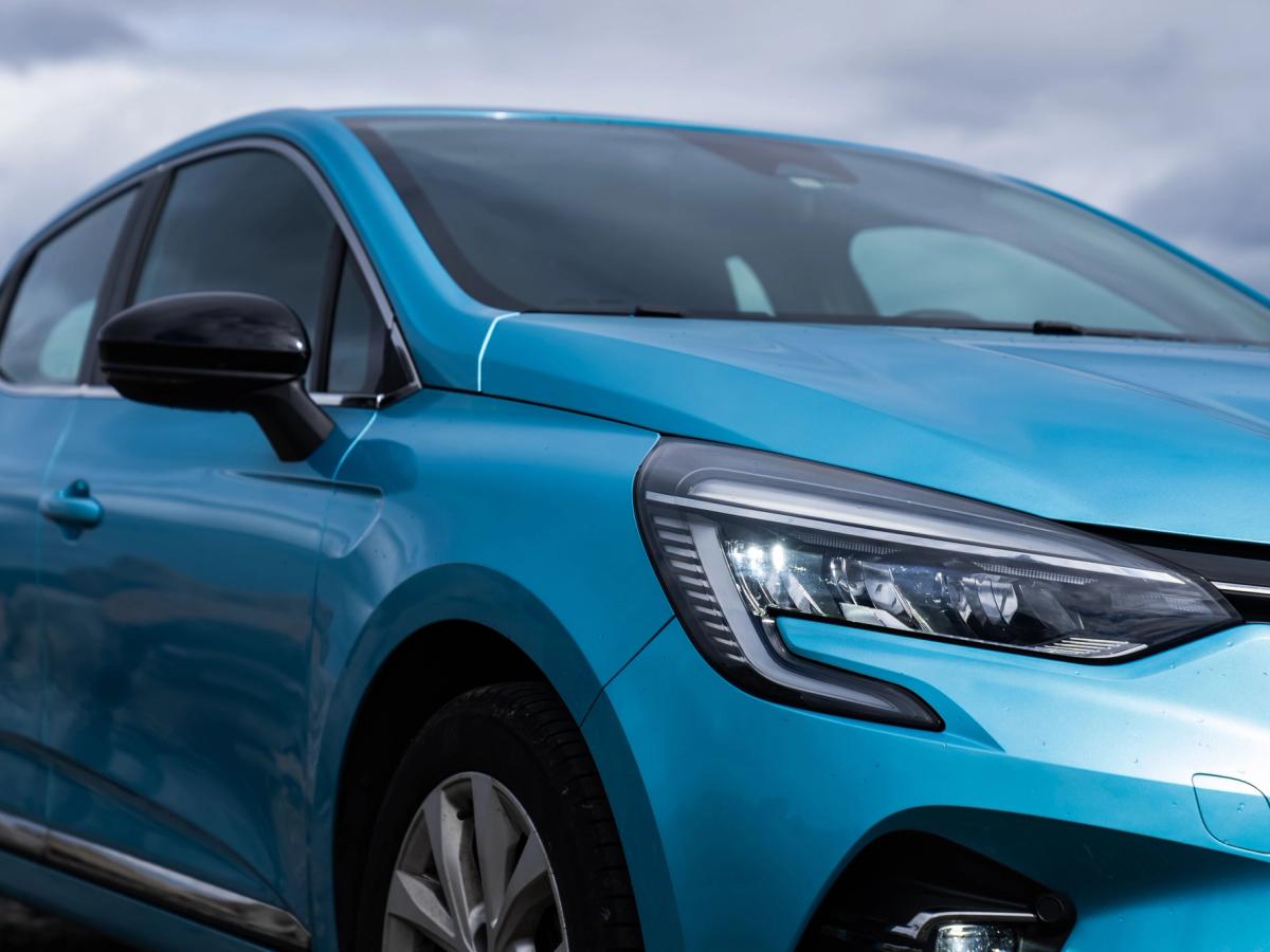 Clio – Detailansicht der vorderen Ecke Nahaufnahme des Frontscheinwerfers und der Motorhaube eines Renault Clio vor bewölktem Himmel