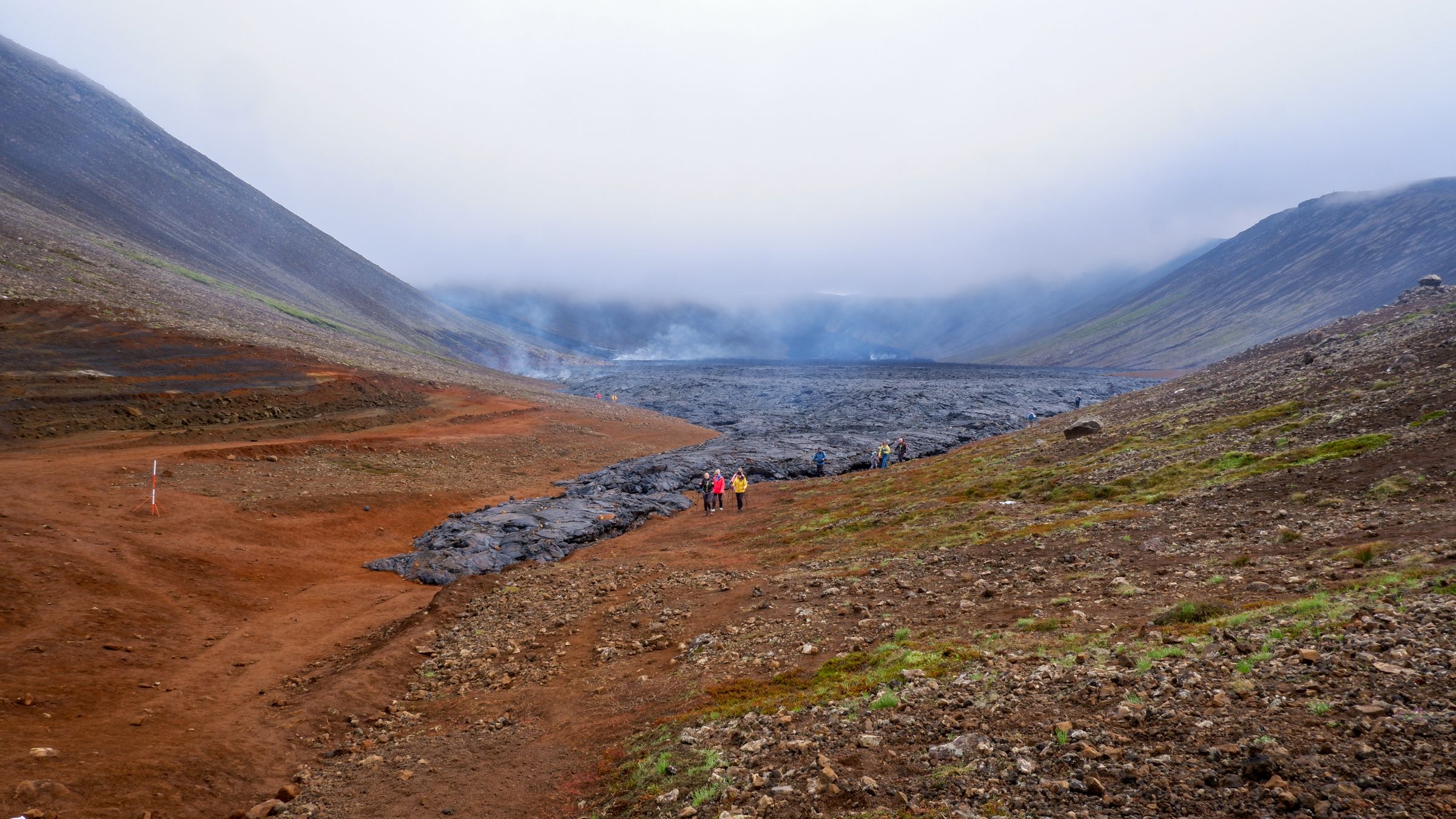 a group of people are walking down a lava field in the mountains .