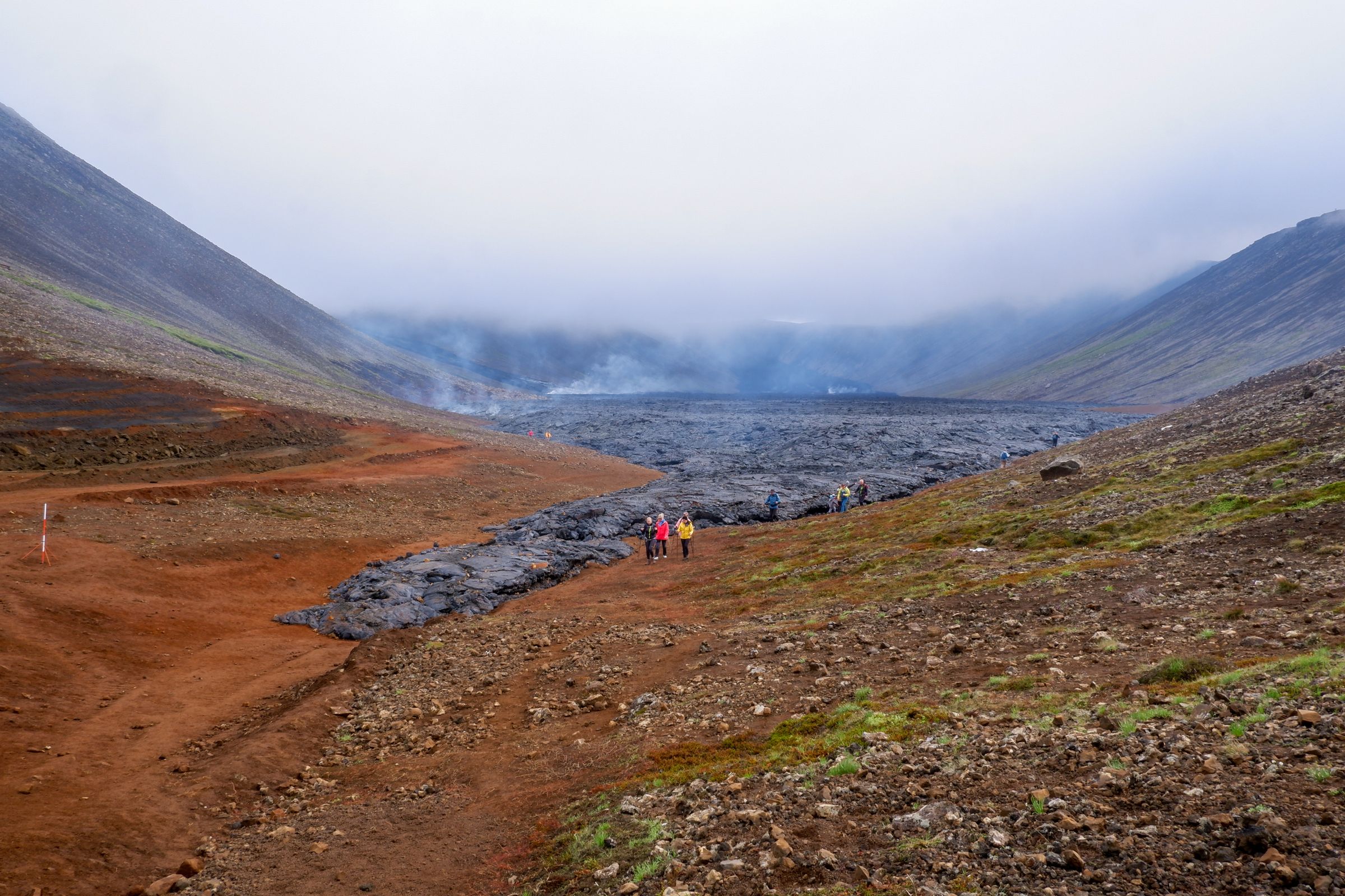 a group of people are walking down a lava field in the mountains .