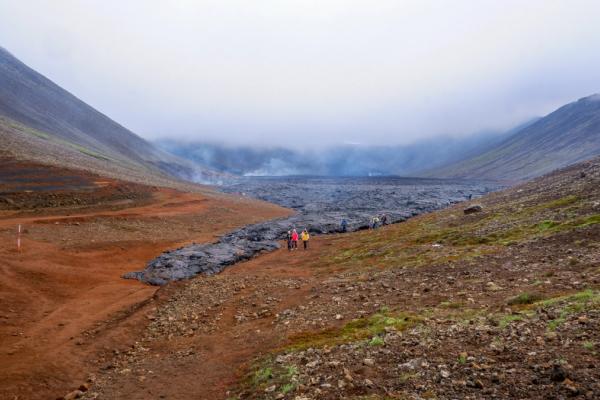 a group of people are walking down a lava field in the mountains .