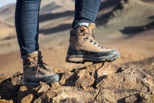 a person wearing hiking boots is standing on a rock .
