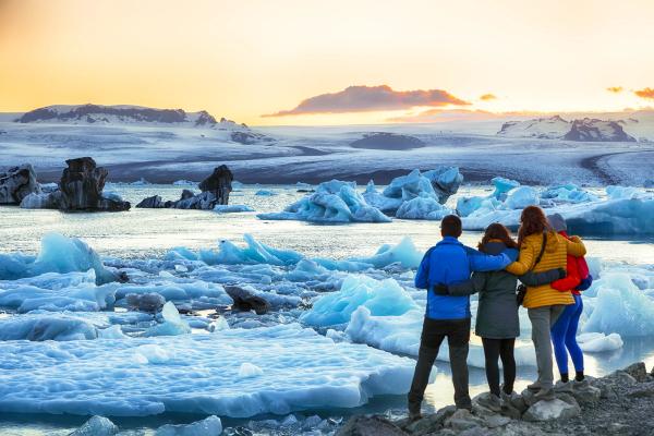 4 personas de espaldas a la cámara viendo una laguna glaciar