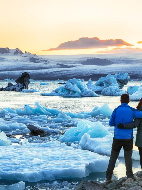 4 personas de espaldas a la cámara viendo una laguna glaciar