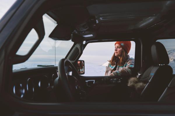 Renting a car in iceland woman standing near her iceland rental car thinking about her trip