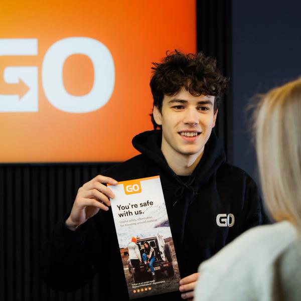 Un chico sosteniendo un panfleto que dice "you 're safe with us"