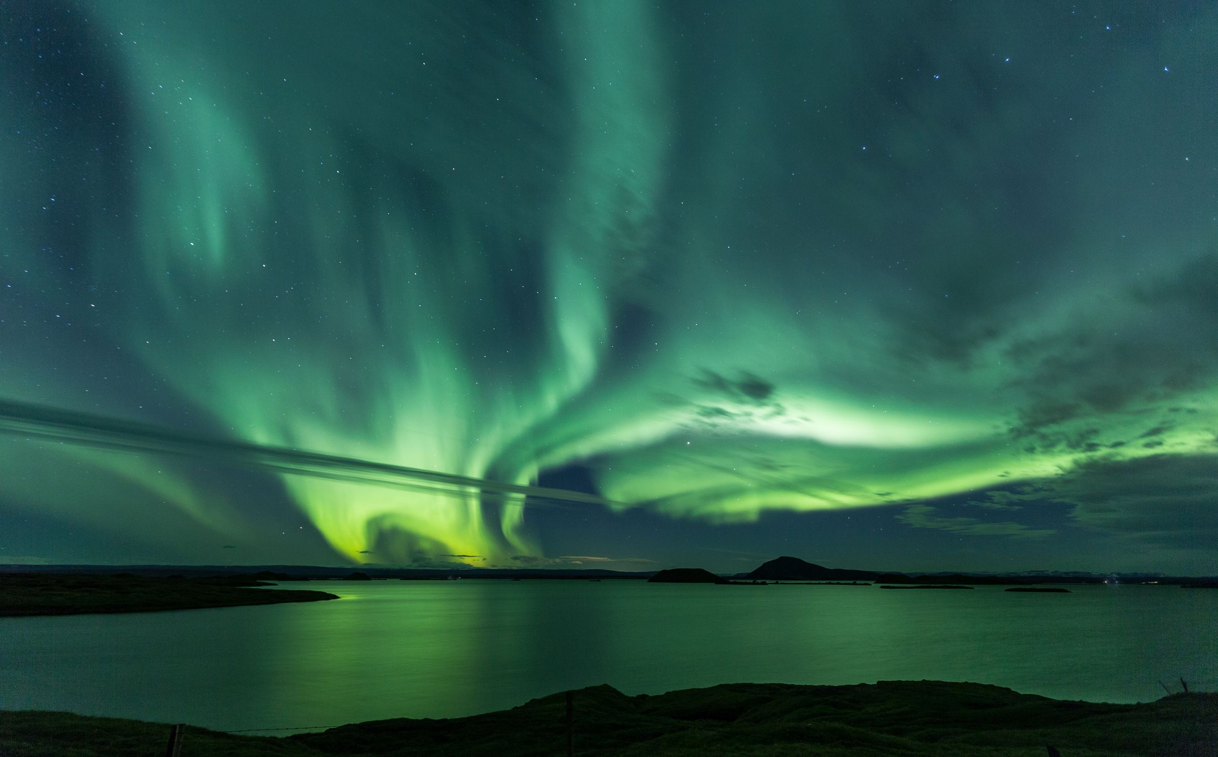 the aurora borealis is dancing in the night sky over Lake Myvatn