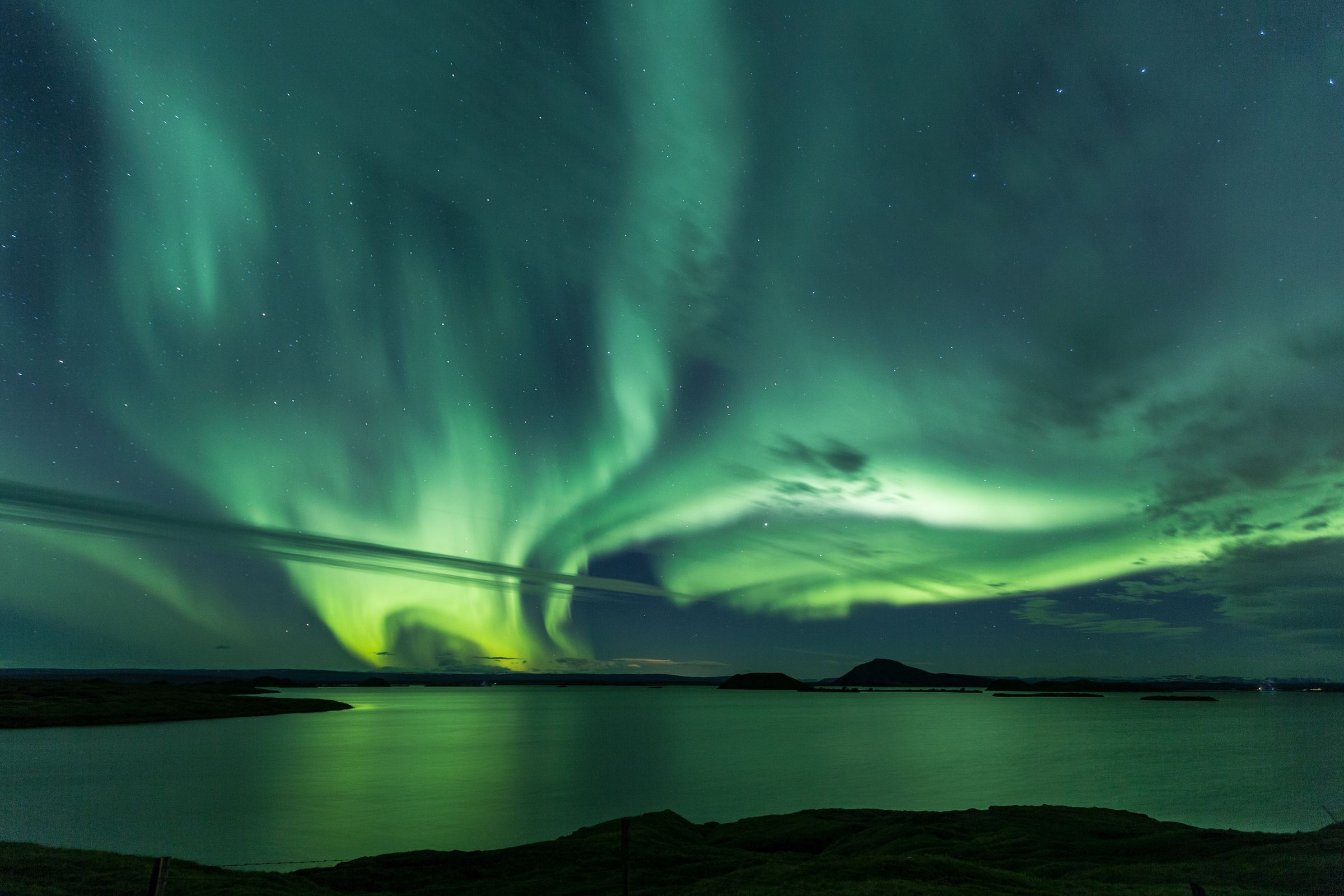 the aurora borealis is dancing in the night sky over Lake Myvatn