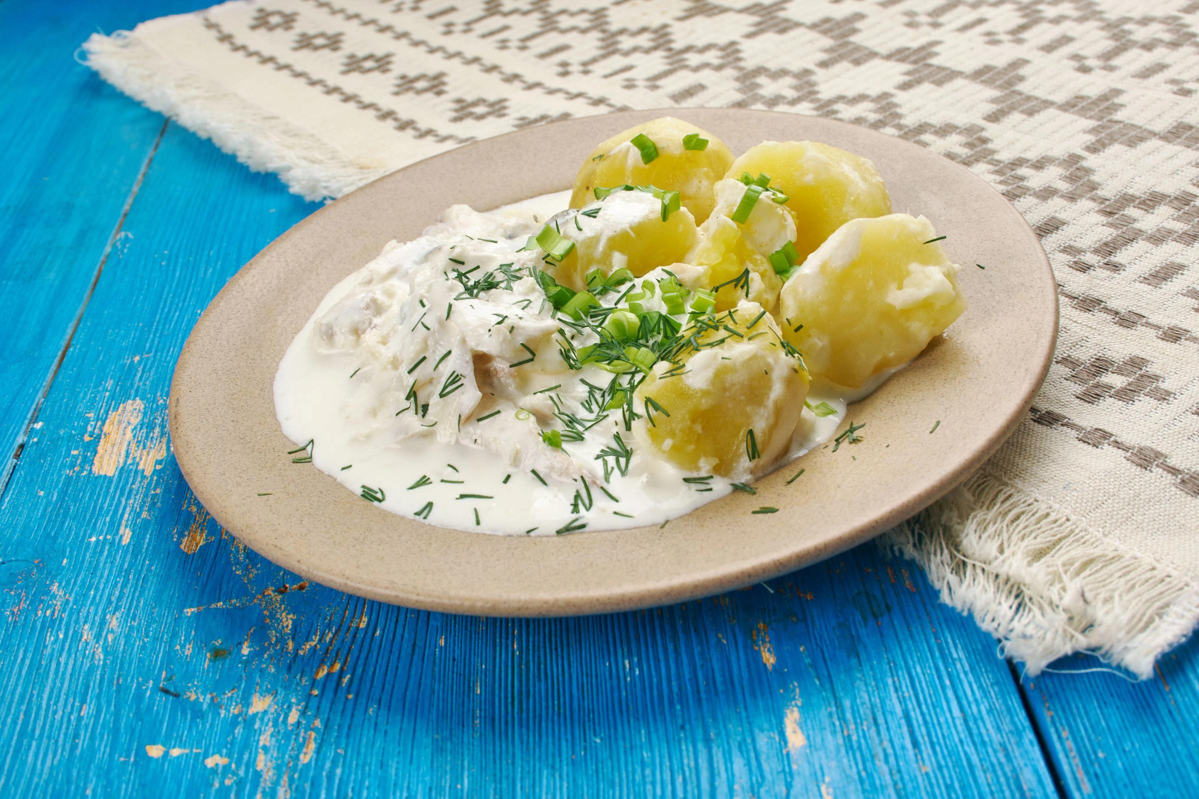 a plate of potatoes with sour cream and dill on a blue wooden table .