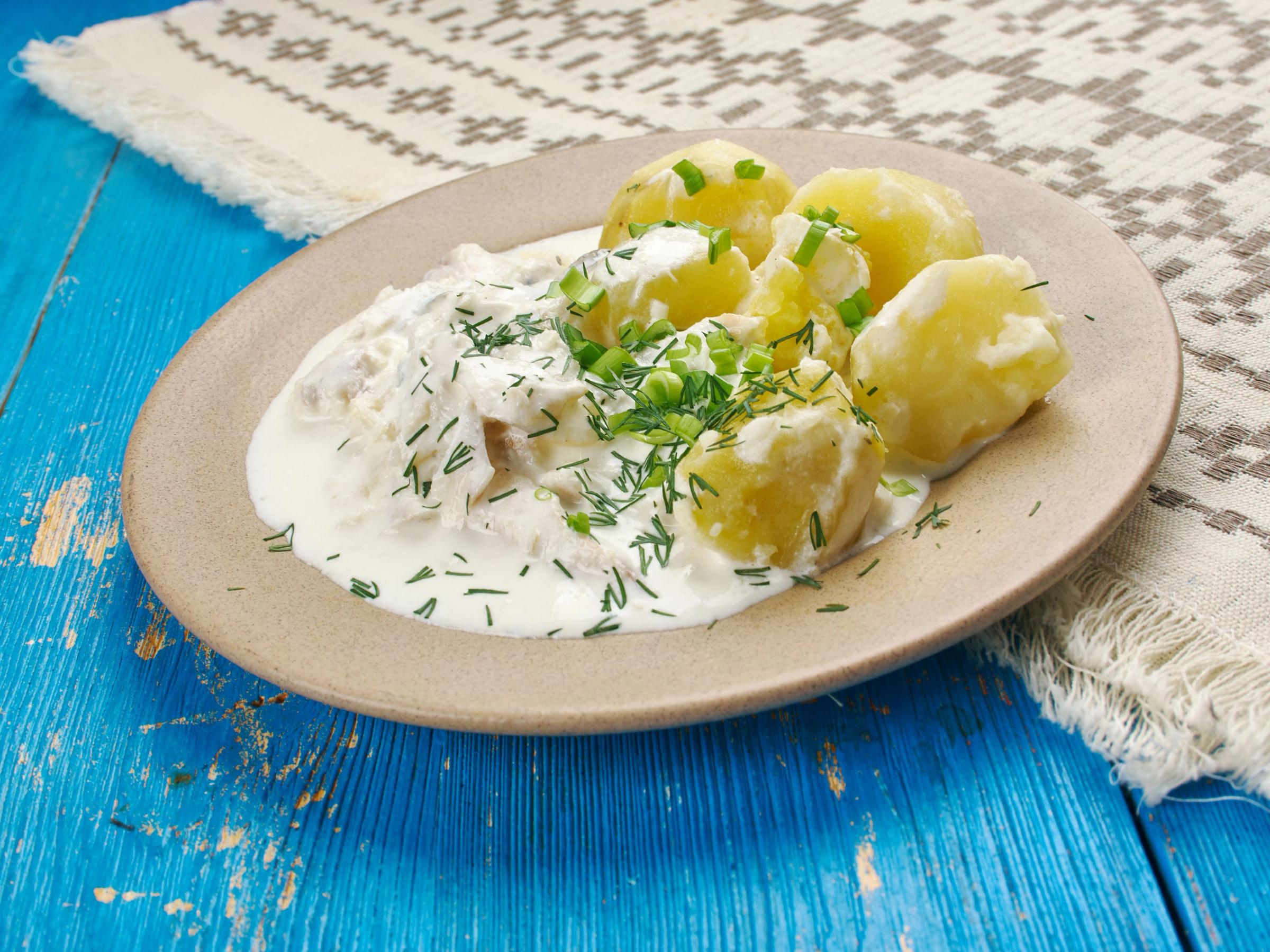 a plate of potatoes with sour cream and dill on a blue wooden table .