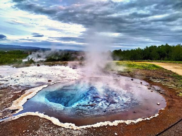 a large hole in the ground with steam coming out of it .