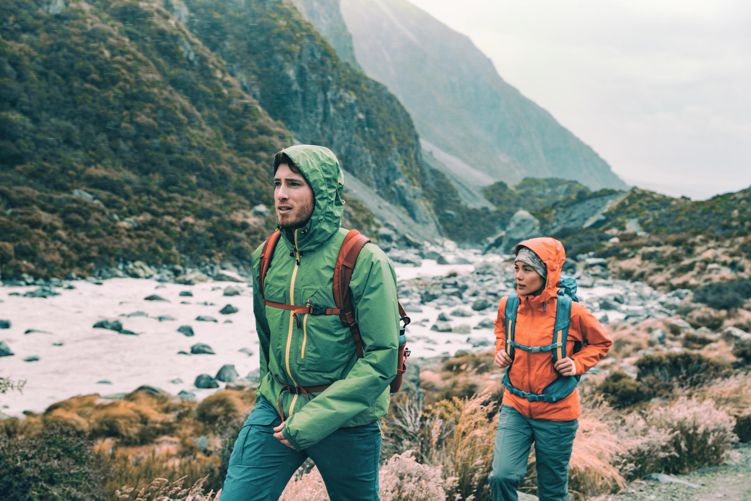 a man and a woman are hiking in the mountains .