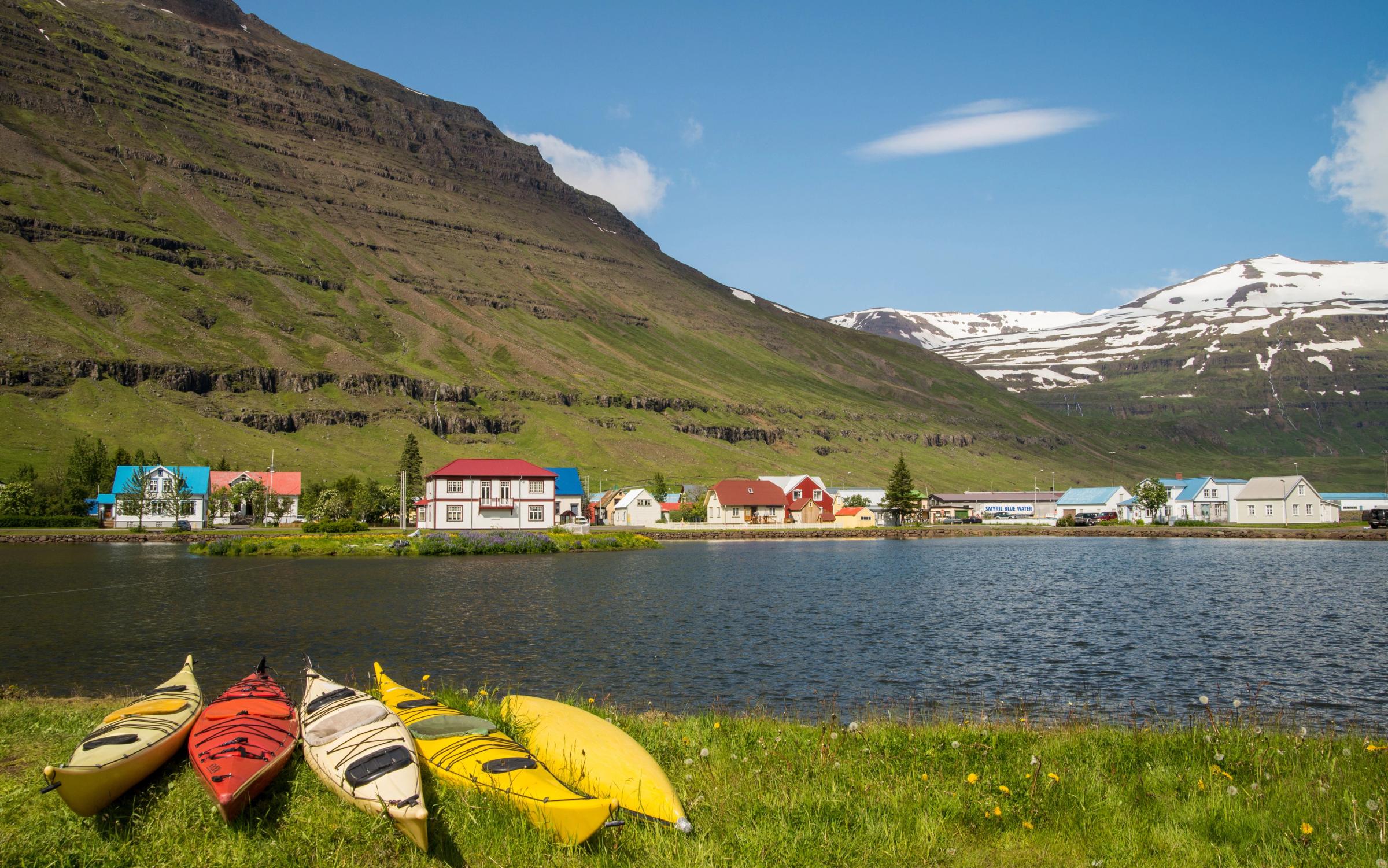 Kayaks in the shore of a fjord with Seyðisfjörður on the other side
