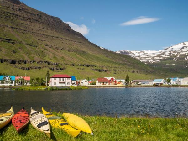 Kayaks in the shore of a fjord with Seyðisfjörður on the other side