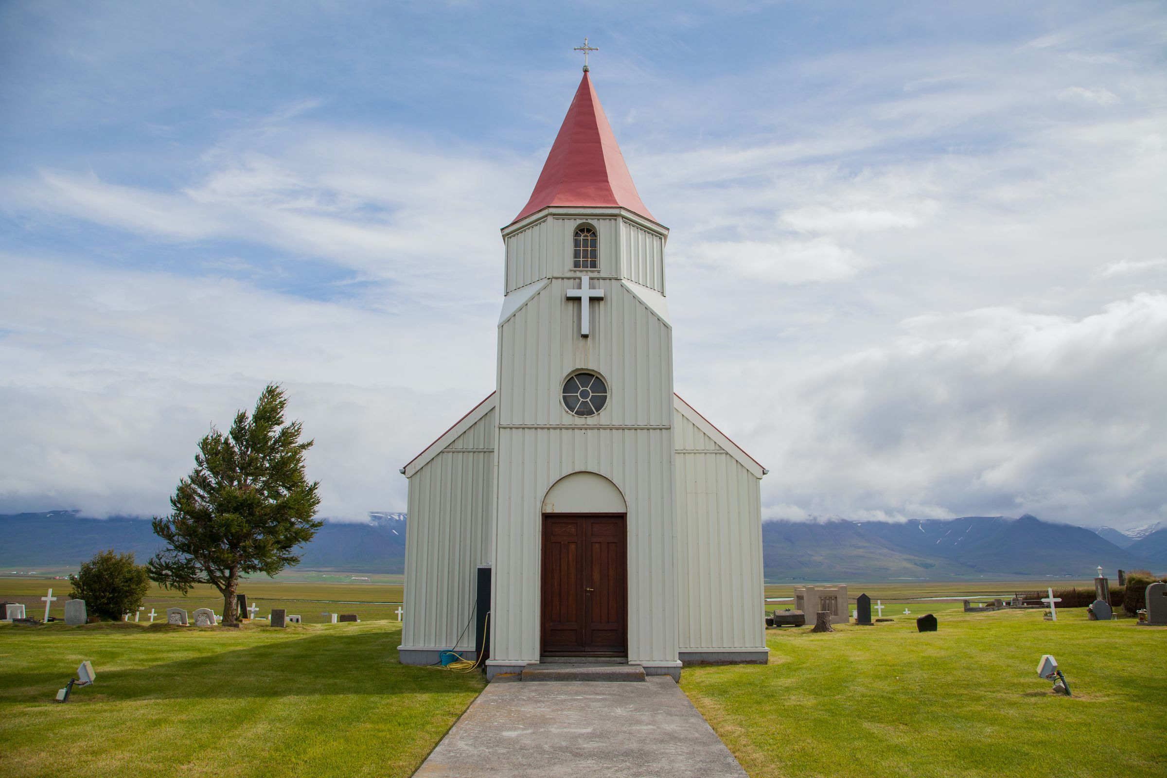 a small white church with a red roof and a cross on top at glaumbær in north iceland.