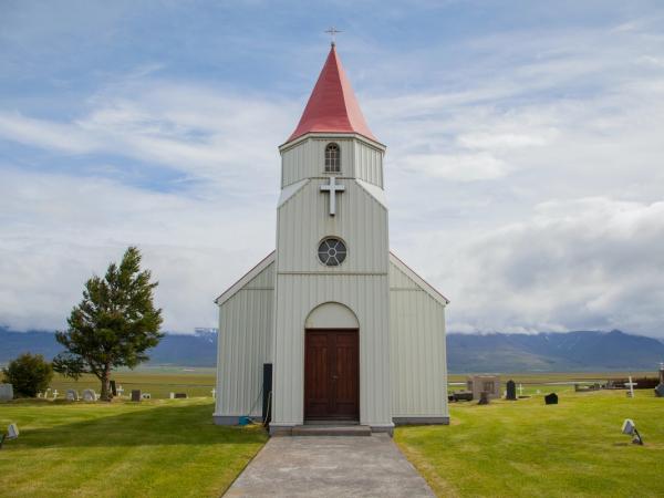 a small white church with a red roof and a cross on top at glaumbær in north iceland.