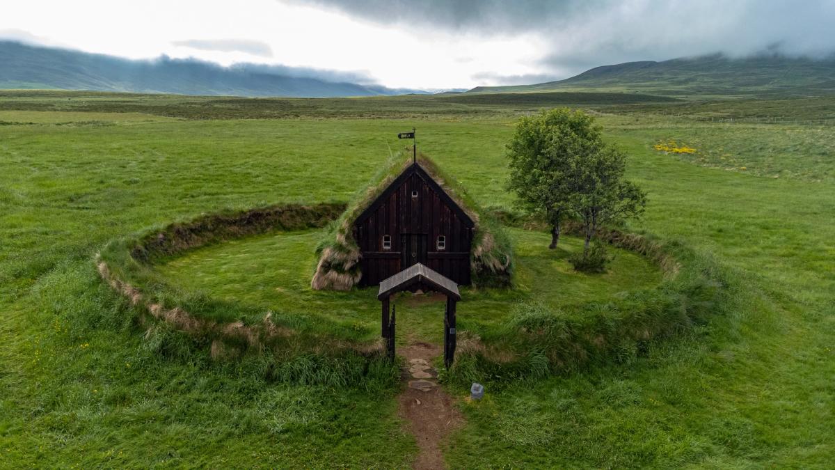 an aerial view of a small church in the middle of a grassy field .