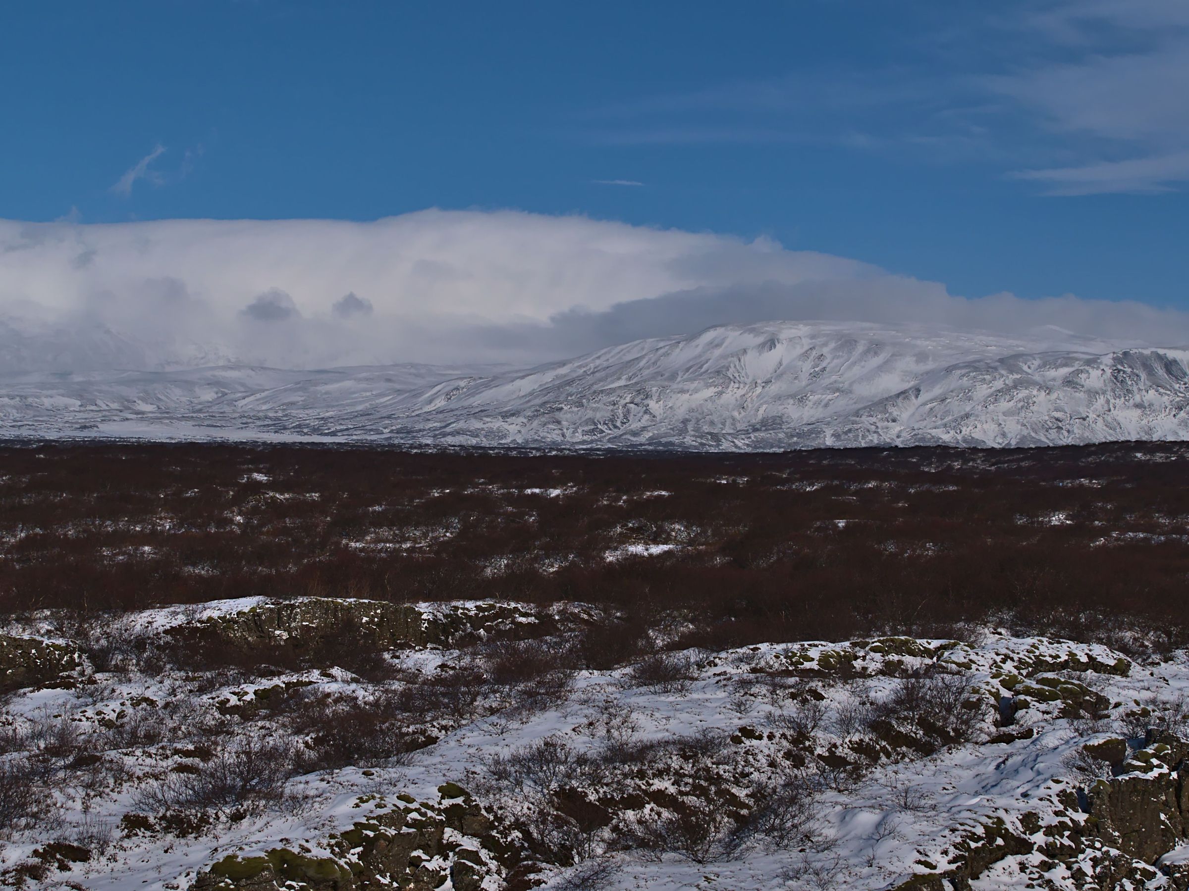 a snowy landscape with mountains in the background and a blue sky