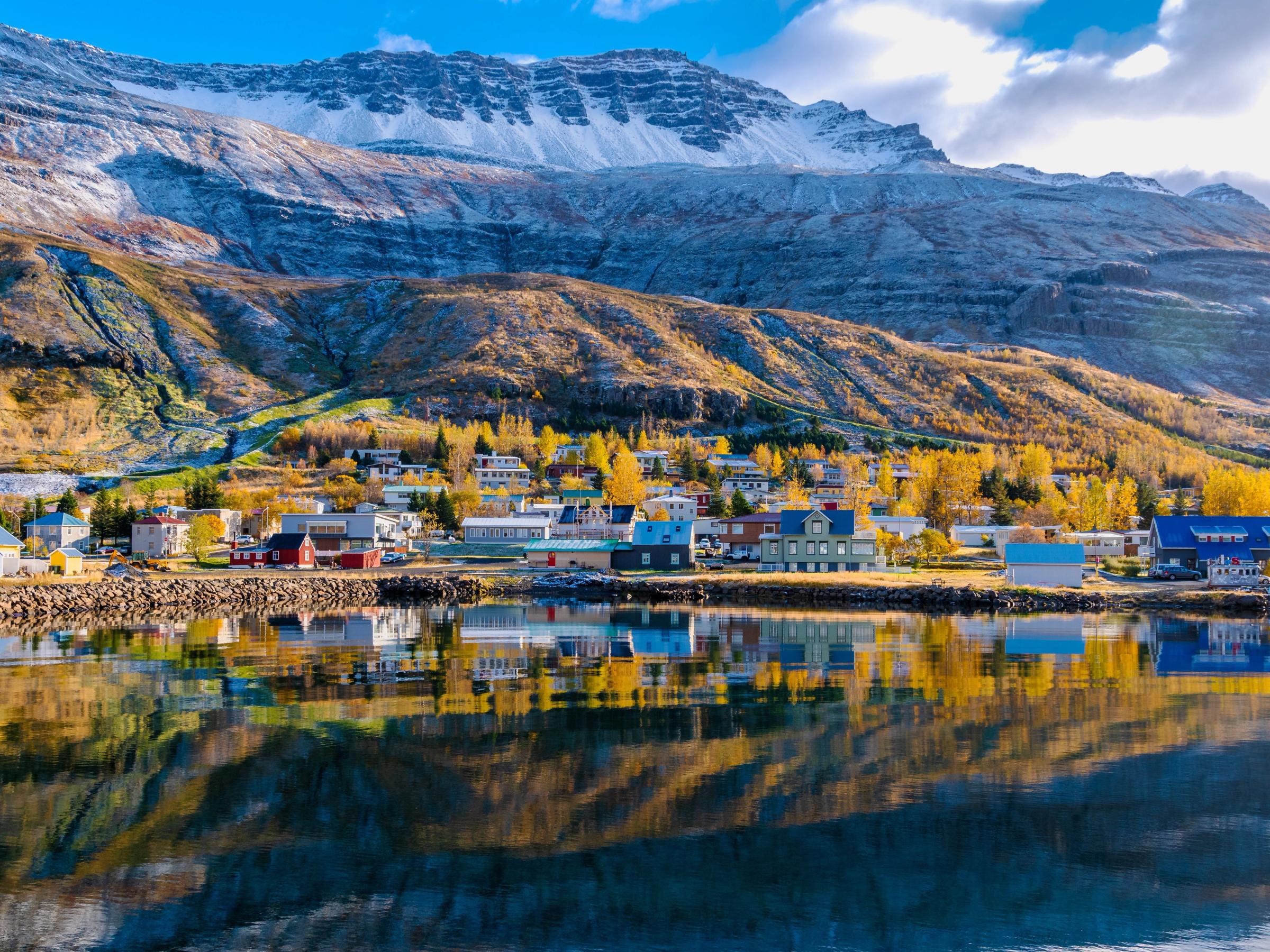 un pequeño pueblo en la orilla de un lago con montañas al fondo .