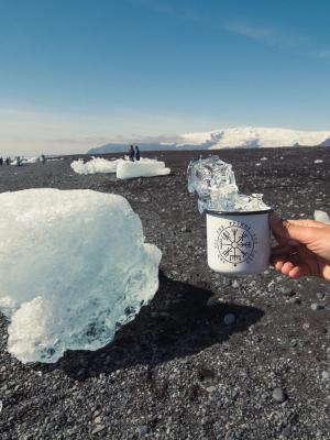a person is holding a cup of coffee on a beach .