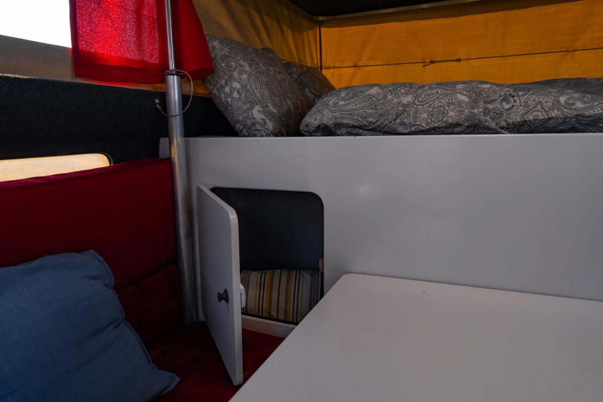 Under-Bed Cupboard Open Small cupboard under the over-cab bed opened to show storage behind the dinette table