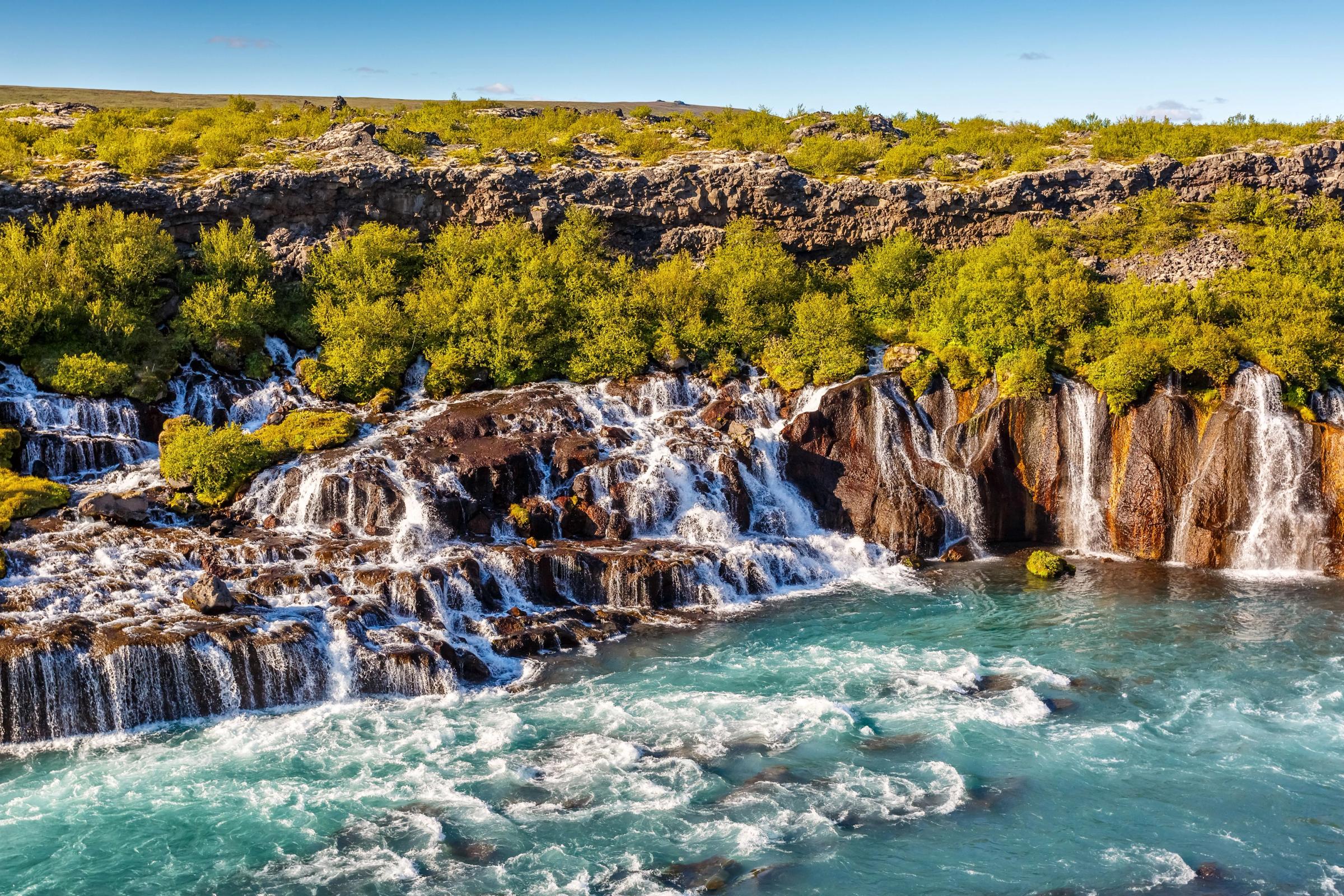 Series of waterfalls cascading down to a turquoise river