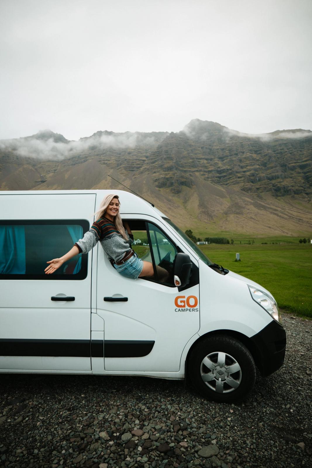 a woman leans out of the window of a go camper van