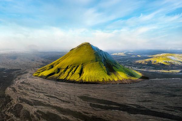 an aerial view of Mælifell mountain with a blue sky in the background .