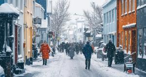 un grupo de personas camina por una calle nevada en una ciudad .