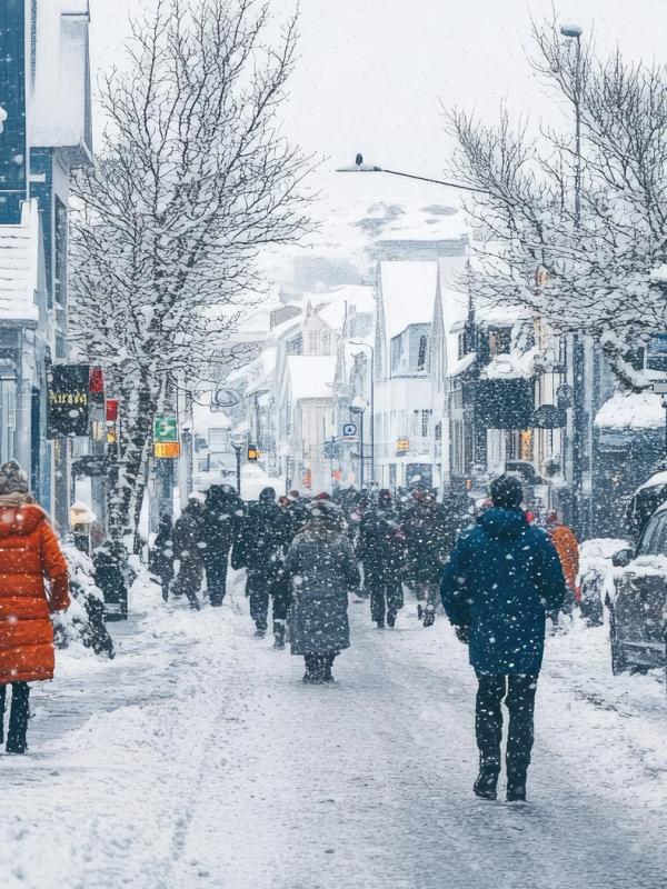 un grupo de personas camina por una calle nevada en una ciudad .